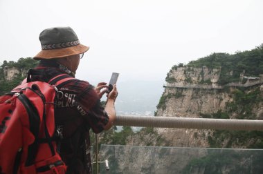 Han, Çin - 16 Haziran 2023: Tanımlanamayan erkek turistler Yuntaishan Parkı 'nda fotoğraf çekiyorlar. Dünyanın ilk jeolojik miras bölgesi olarak listelenmiştir..