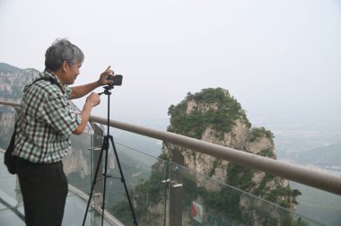 Han, Çin - 16 Haziran 2023: Tanımlanamayan erkek turistler Yuntaishan Parkı 'nda fotoğraf çekiyorlar. Dünyanın ilk jeolojik miras bölgesi olarak listelenmiştir..