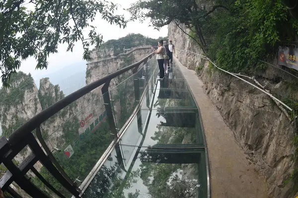 HENAN, Çin - 16 Haziran 2023: Tanımlanamayan turistler Çin 'in Henan Eyaleti' ndeki en güzel jeoloji parkı olan Yuntaishan Parkı 'nda cam gökyüzünde yürürler. Dünyanın ilk jeolojik miras bölgesi olarak listelenmiştir..