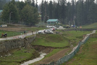 JAMMU AND KASHMIR , INDIA - MAY 10 , 2019 : Tourists are walking on the path leading to the starting point for the cable car station to Gulmarg. Which is famous in the world for its true natural beauty.