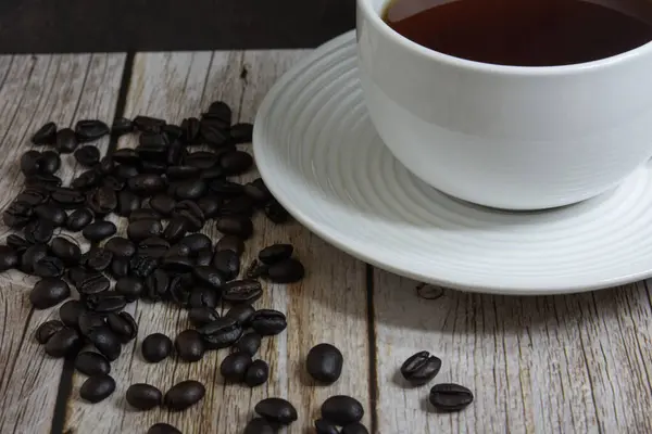 Kavrulmuş kahve çekirdekleri, eski bir cep saati ve deri ciltli bir kitapla çevrili, sade, sade bir kahve bardağının yakın çekimi. Rahat bir sabah atmosferi, rahatlamak için mükemmel, ve kafein aşıkları