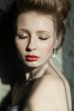 Zarif ve sofistike bir güzel fotoğraf. Makyajla süslenmiş bir model. Zarif mücevherler, kapalı gözler.