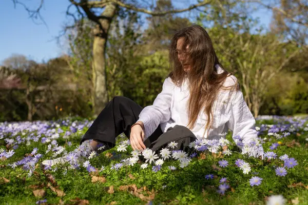 Huzurlu ve huzurlu genç bir kadın, doğanın güzelliğinde canlı çiçeklerle çevrili huzurlu bir anın tadını çıkarır.