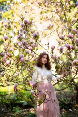 Rüya gibi ve büyüleyici bir bahar fotoğrafı çiçek açan manolya ağaçlarının arasına yerleştirilmiş zarif bir kadını sergiliyor.