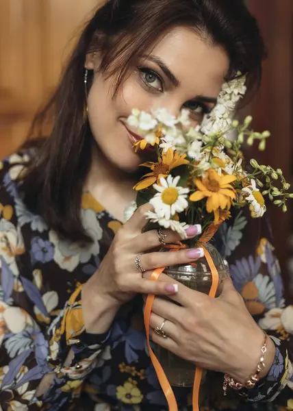 Neşeli bir kadın renkli bir buket tutar, sıcak dekorlu sıcak bir iç mekanda mutluluk saçar.