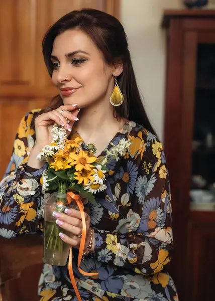 Neşeli bir kadın renkli bir buket tutar, sıcak dekorlu sıcak bir iç mekanda mutluluk saçar.