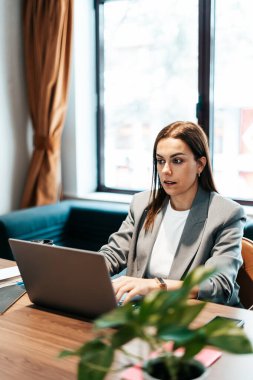 Ofiste çalışan ve dizüstü bilgisayarda yazan bir kadın.