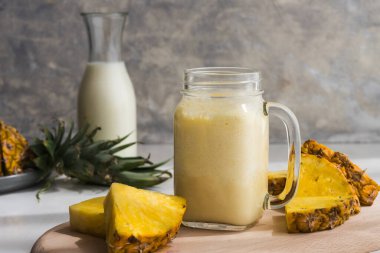 Gri arka planda cam bir kavanozda sağlıklı ananas kokteyli.