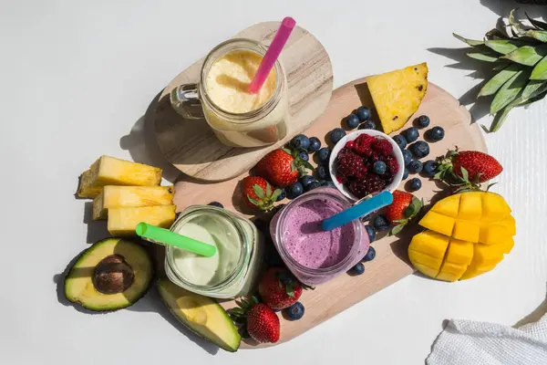 Renkli smoothie, sağlıklı detoks vitamin diyeti veya vegan gıda konsepti, taze vitaminler, avokadolu kahvaltı içeceği, ananas, mango, çilek, yabanmersini