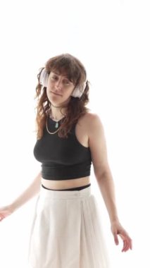 Kadın kulaklıkla müzik dinlerken pencerenin önünde dans ediyor..