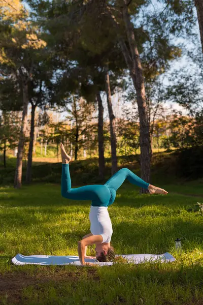 Genç kadın parkta yoga yapıyor.