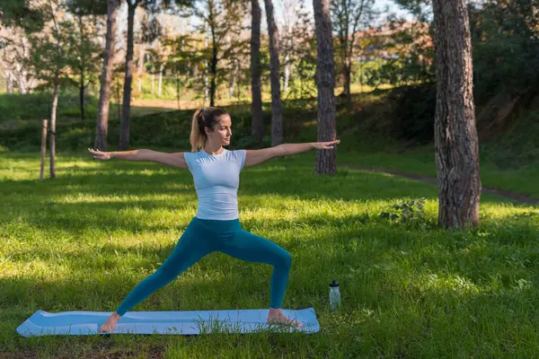 Genç kadın parkta yoga yapıyor.