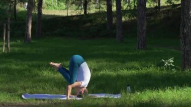 Genç kadın parkta yoga yapıyor.