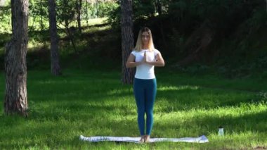 Genç kadın parkta yoga yapıyor.