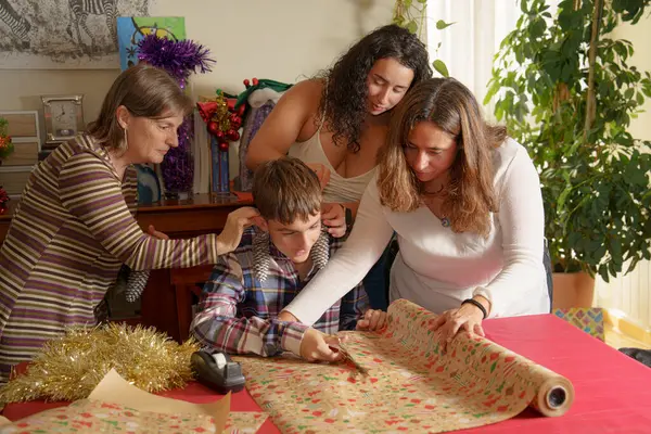 Dört kişinin hediye paketlediği bir aile toplantısı. Üç kadın ona yardım ederken, bir çocuk ambalaj kağıdı kesmeye odaklanıyor. Torbada süslemelerle şenlikli bir atmosfer sergiliyor.
