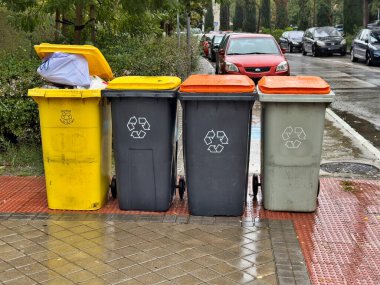 Dört çöp tenekesi kaldırıma dizilmiş, birinde 