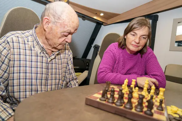 Yolculukları sırasında karavanlarında satranç oynayan konsantre yaşlı çift, boş zamanlarının tadını çıkarıyorlar.