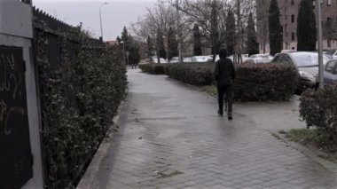 İspanya 'nın Madrid semtinde siyah elbiseli genç bir adam siyah bir köpeği gezdiriyor.