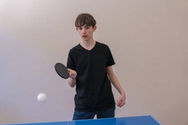 Genç, masa tenisi oynuyor. Kapalı alanda oynanacak heyecanlı bir maça hazırlanırken küreğini ustalıkla sallıyor.