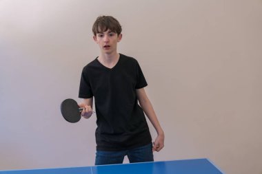 Genç adam masa tenisi oynarken topa odaklandı, raketi sıkıca kavradı ve oyunda yetenek ve konsantrasyon sergiledi.