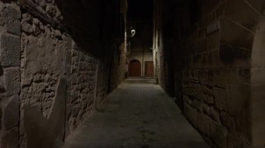 Taş duvarlar ve kaldırım taşları İspanya 'nın Kretas kentindeki gece sokak lambalarıyla aydınlatılmış pitoresk bir ara sokağı karakterize ediyor.