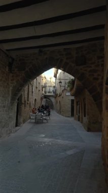 Turistler dinleniyor, tarihi taş kemer altında sohbet ediyorlar, İspanya 'nın Kretas köyünde dinlenen anları yakalıyorlar.