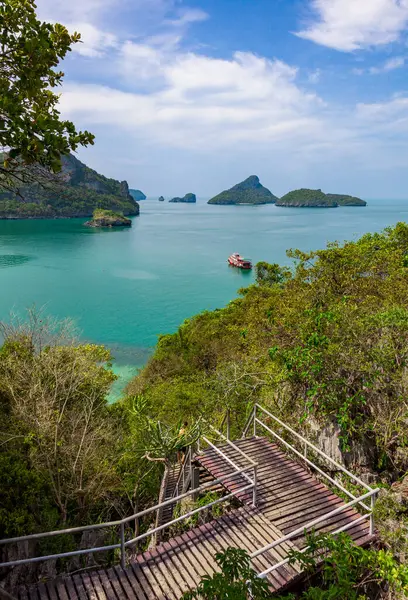 Ulusal park adalarından birinin yamacından arka plandaki adalar, merkezdeki gemi ve ön plandaki turkuaz su ve yemyeşil yapraklar üzerinde güzel bir manzara vardır. Güneşli güzel bir günde çekilen.