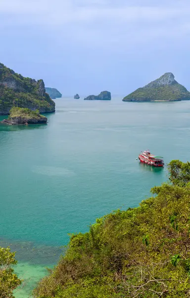 Tayland 'daki Mu Ko Ang Tanga Ulusal Deniz Parkı' nın turkuaz sularında küçük bir gemi yüzmektedir. Bereketli yeşil adalar ve açık mavi gökyüzüyle çevrili bu tropikal cennet büyüleyici manzaralar, huzurlu manzaralar ve unutulmaz bir kaçış sunuyor..