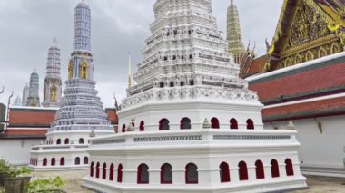 Tayland 'daki bir tapınak (Büyük Saray) kompleksinin karmaşık mimarisi, dekoratif tasarımlarla birden fazla pagoda içerir. Huzurlu atmosfer, bölgenin zengin kültürel mirasını ve manevi önemini yansıtıyor..