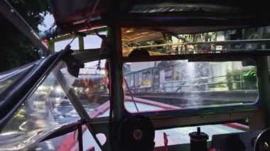 Alacakaranlıkta sessiz bir su yolunda süzülen bir teknenin içinde. Yumuşak yansımalar ve sıcak ışıklar sakin bir ortam yaratarak, kentsel yaşamla iç içe geçmiş doğanın güzelliğini gözler önüne seriyor. Sürücü POV 'tan çekilmiş..