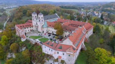 Bu çarpıcı hava görüntüsü, Polonya 'nın tarihi Benedictine Manastırı' nı çekiyor. Yeşillik ile çevrelenmiş ve kendine özgü mimarisi ile karakterize edilmiş bu alan doğa ve tarihin mükemmel bir karışımını temsil ediyor..