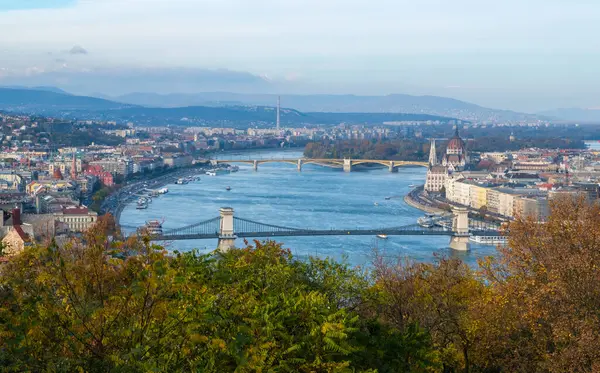 Güzel Tuna Nehri Budapeşte 'den akıyor, ikonik köprüler ve tarihi mimari astarlı bankalar. Sonbahar yapraklarının canlı renkleri şehrin büyüleyici manzarasını güçlendiriyor..