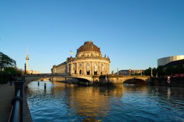 Bode Müzesi, Berlin 'deki nehir boyunca akşam ışıklarıyla aydınlanan görkemli bir şekilde duruyor. Bu tarihi bina sanat eserlerini sergiliyor, sudaki yansımalarla manzaralı bir zemin sağlıyor..