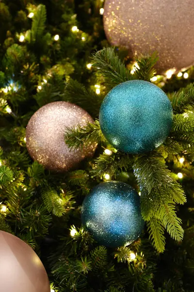 Bu resimde, bereketli bir Noel ağacını süsleyen mavi ve pembe tonlarda ışıltılı süsler var. Yumuşak beyaz ışıklar festival atmosferini güçlendirir, sıcak ve davetkar bir tatil sahnesi yaratır..