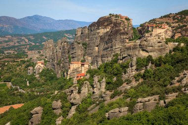 Meteora kompleksi, yemyeşil ve görkemli dağ manzaralarıyla çevrili ve Yunanistan 'da nefes kesen tarihi ve doğal manzaraları temsil eden antik manastırların tepesinde yükselen kaya oluşumlarına sahip..