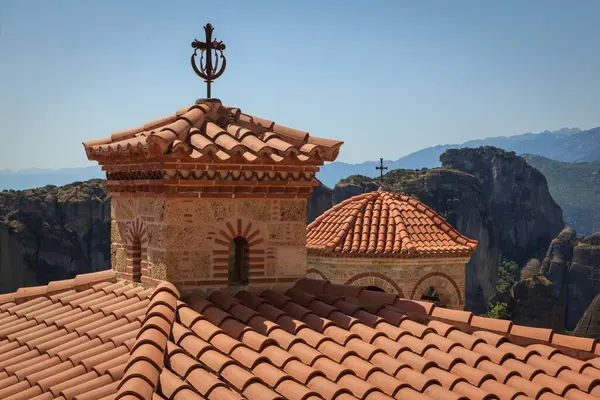 Meteora Manastırı 'nın eşsiz çatıları, yüksek uçurumlar ve dağlarla çevrili. Terracotta fayansları ve haçların karışımı bu UNESCO Dünya Mirası sahasının tarihi ve ruhani önemini vurguluyor..