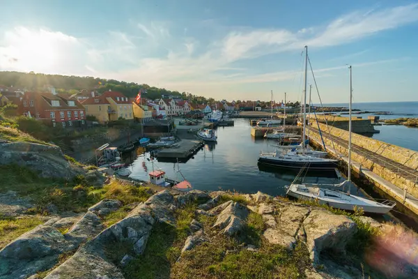 Huzurlu bir liman boyunca canlı evler barındıran pitoresk bir sahil köyü. Gemiler rıhtımlarda demirli, kayalık arazi, batan güneşin sıcacık parıltısıyla aydınlatılıyor. Gudhjem, Bornholm, Danimarka.