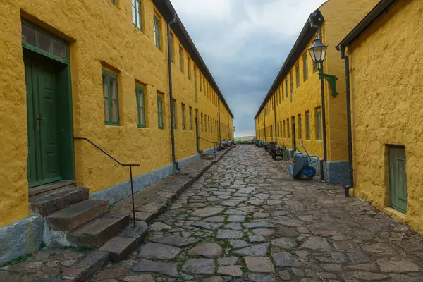Dar bir kaldırım taşı caddesi yeşil aksanlı büyüleyici sarı binalarla çevrili. Sahne barışçıl ve tarihi bir ortam yakalıyor, mimarinin keşfedilmesi ve takdir edilmesi için davet ediliyor. Hıristiyanlar, Bornholm, Danimarka