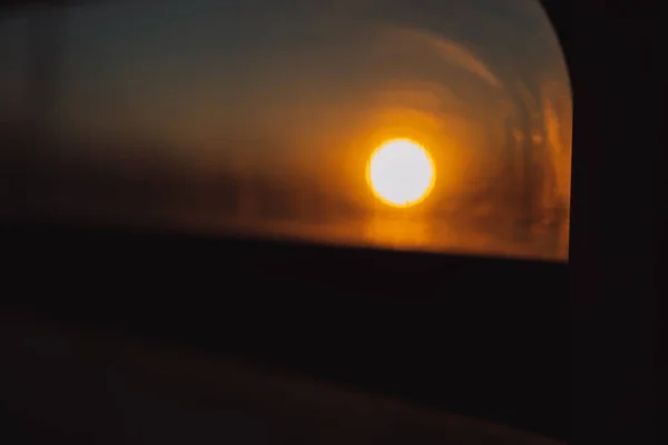 Sun at dawn through the window of a train car.