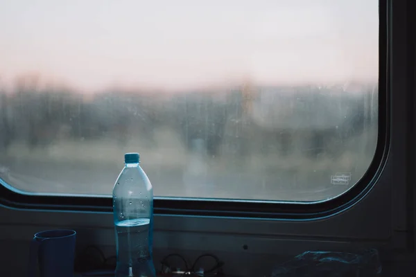Bottle of water in front of the train compartment window.