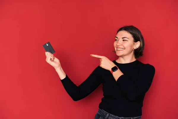 stock image Lady points her finger at credit card in her hand against red background.