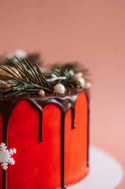 Noel kırmızı pastası, pembe arka planda bir Noel ağacının dallarıyla çikolata kaplı..