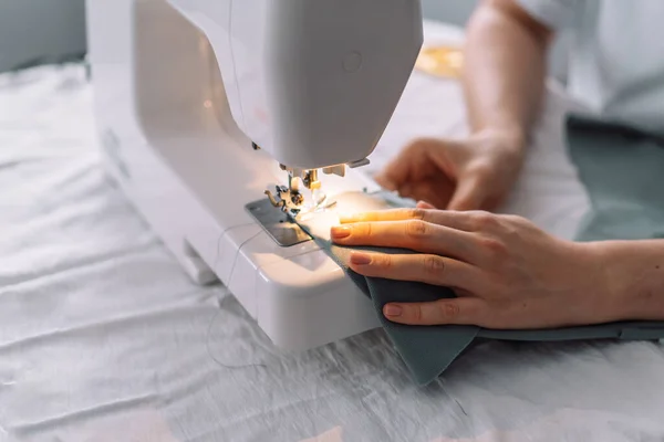 Lady stitching the edges of the fabric of a sewing machine.