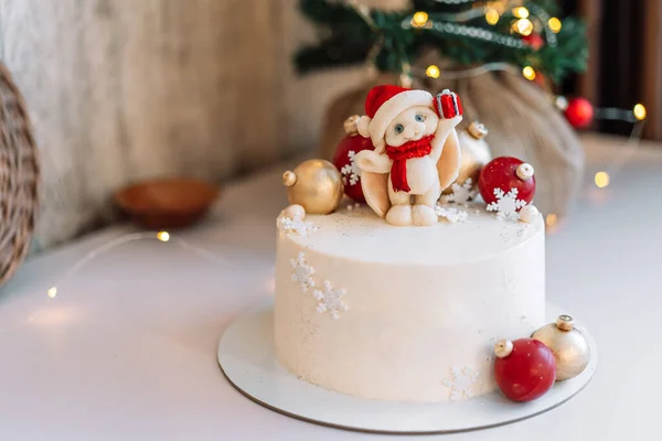 Karamelli Tavşanlı Beyaz Noel Pastası Çelenklerin Işıklarının Önünde Toplar — Stok fotoğraf