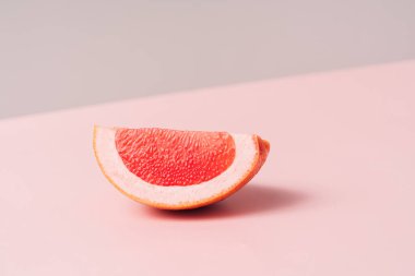 Grapefruit slice on pink background.