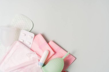 Supplies for the menstrual cycle on a green background.
