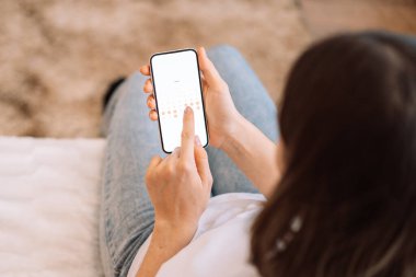 Lady notes in the smartphone the days of the calendar menstrual cycle.