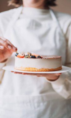 Lady confectioner in white uniform holding birds milk cake.