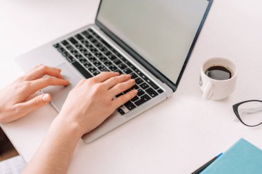 Lady typing on laptop keyboard at table.