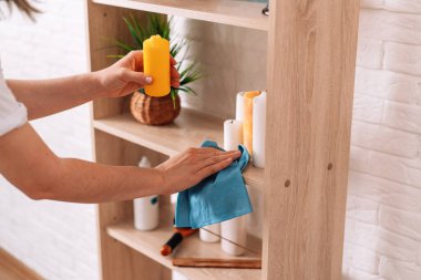 Lady with a rag in her hands cleans the shelves of the locker.